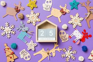 festivo decorazioni e giocattoli su viola sfondo. superiore Visualizza di di legno calendario. il venti quinto di dicembre. allegro Natale concetto foto