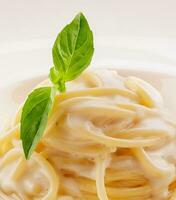 spaghetti con bianca crema salsa su bianca piatto foto