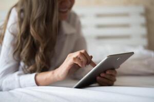 donna felice sdraiata sul letto con computer tablet foto