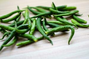 fresco verde chili Pepe su pianura di legno tavolo, verde essenziale verdure per tutti essenziale Alimenti, Visualizza di non pelati verdure con pianura sfondo foto