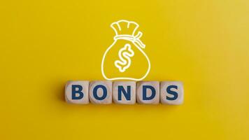 obbligazioni parola su di legno cubi con i soldi Borsa su giallo sfondo. obbligazioni crescente concetto. foto