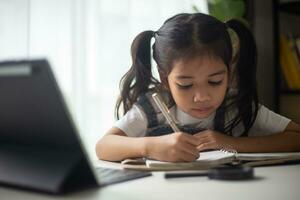 giovane asiatico carino ragazza studiando con il computer portatile a casa. in linea apprendimento concetto. foto