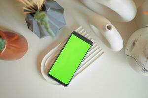 inteligente Telefono con verde schermo e casa interno decorazione su tavolo foto