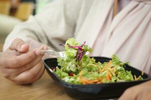 donne mangiare insalata nel un' plastica ciotola all'aperto foto