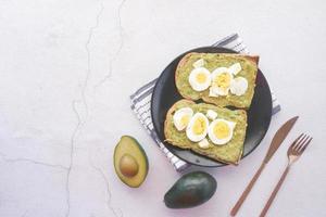 avocado e uovo su fetta di pane nero su sfondo bianco foto