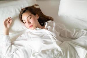 ritratto bella donna asiatica che dorme sul letto con cuscino bianco foto