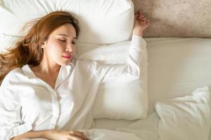 ritratto bella donna asiatica che dorme sul letto con cuscino bianco foto