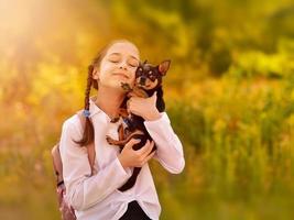 bambina studentessa che tiene e gioca con il cane. gli amici. foto