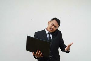 ritratto giovane asiatico uomo d'affari multitasking, chiamata con mobile Telefono mentre Lavorando con il computer portatile isolato su bianca sfondo foto