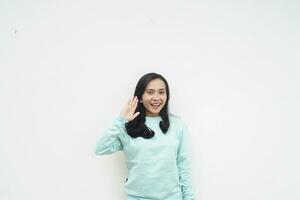 ritratto indonesiano bellissimo donna indossare leggero blu maglione con saluto gesto dire Ciao isolato su bianca sfondo foto