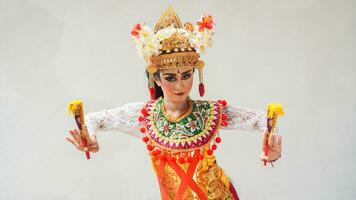 ragazza indossare balinese tradizionale vestito con un' danza gesto su bianca sfondo con -Tenuto in mano fan, corona, gioielleria, e oro ornamento Accessori. isolato balinese ballerino donna ritratto foto