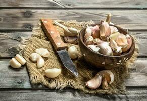 Chiodi di garofano di aglio nel un' ciotola con un' coltello. foto