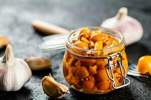 marinato funghi nel un' bicchiere vaso con Chiodi di garofano di aglio. foto