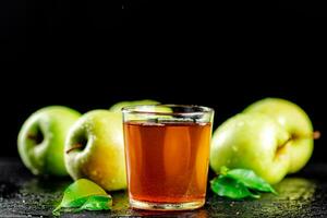 un' bicchiere di verde Mela succo con le foglie su il tavolo. foto