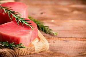 un' bistecca di crudo tonno su un' taglio tavola con un' rametto di rosmarino. foto