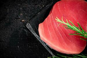 crudo tonno su un' pietra tavola con rosmarino. foto