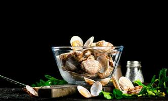 fresco vongole nel il ciotola su un' taglio tavola con prezzemolo. foto