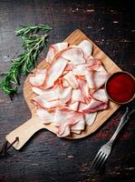 pezzi di Bacon su un' taglio tavola con pomodoro salsa. foto