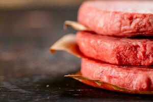 crudo hamburger su carta. su un' rustico buio sfondo. foto