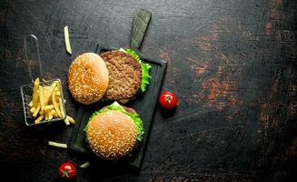 hamburger su un' nero taglio tavola e patatine fritte. foto