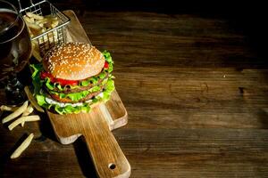 hamburger su un' taglio tavola con birra e patatine fritte. foto