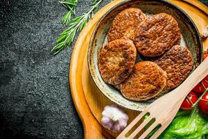 cotolette a il vecchio padella con un' spatola, ciliegia pomodori e insalata le foglie. foto