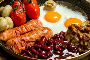 inglese colazione.fritto uova con salsicce, Bacon e rosso in scatola fagioli. foto