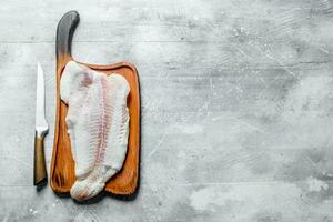 pesce filetto su un' di legno taglio tavola con un' coltello. foto