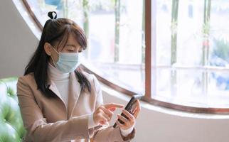 donna d'affari che indossa una maschera chirurgica e usa lo smartphone foto