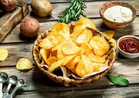 Patata patatine fritte nel un' cestino con diverso salse. foto