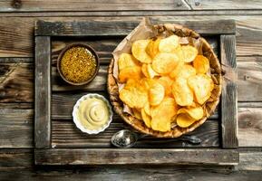 Patata patatine fritte nel un' cestino con diverso salse. foto