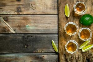 Tequila nel un' tiro bicchiere su un' taglio tavola con fette di lime. foto