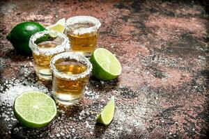 Tequila nel un' tiro bicchiere con sale e affettato lime. foto