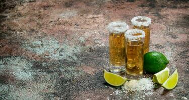 Tequila nel un' tiro bicchiere di sale e lime fette. foto