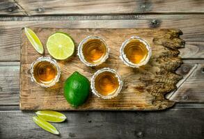 Tequila nel un' tiro bicchiere su un' taglio tavola con lime. foto