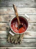 pomodoro salsa nel un' pentola con un' cucchiaio su il taglio tavola. foto