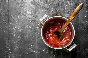 pomodoro salsa nel un' pentola con un' di legno cucchiaio. foto