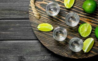 Vodka nel un' tiro bicchiere su un' vassoio con fette di lime. foto