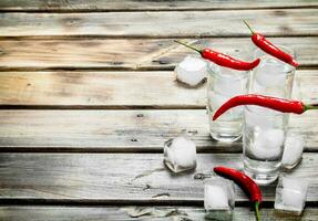 Vodka con ghiaccio nel un' tiro bicchiere e rosso caldo Pepe. foto