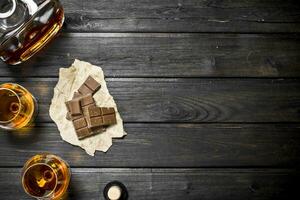 Cognac nel bicchieri e un' bottiglia di amaro cioccolato. foto