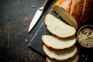 affettato fresco pane con il coltello e il grano nel il ciotola. foto