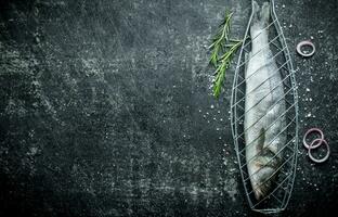 crudo pesce su griglia cremagliera con cipolla anelli e rosmarino. foto