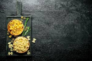 diverso tipi di crudo pasta nel ciotole con il rosmarino. foto