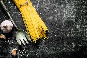 crudo spaghetti con aglio e un' mestolo. foto