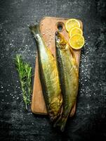 affumicato pesce su un' taglio tavola con Limone e rosmarino. foto