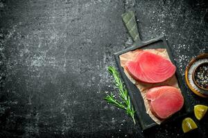 crudo tonno filetto su un' taglio tavola con rosmarino, Limone e spezie. foto