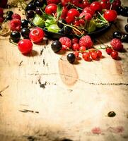 selvaggio frutti di bosco nel il vecchio piatto. su di legno tavolo. foto