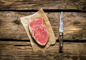 bistecca crudo carne con un' coltello. su di legno sfondo. foto