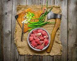 tritato crudo carne con fresco cipolle e un ascia su un vecchio tessuto. foto