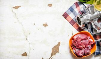 crudo carne con un' mano macinino su il tessuto. foto